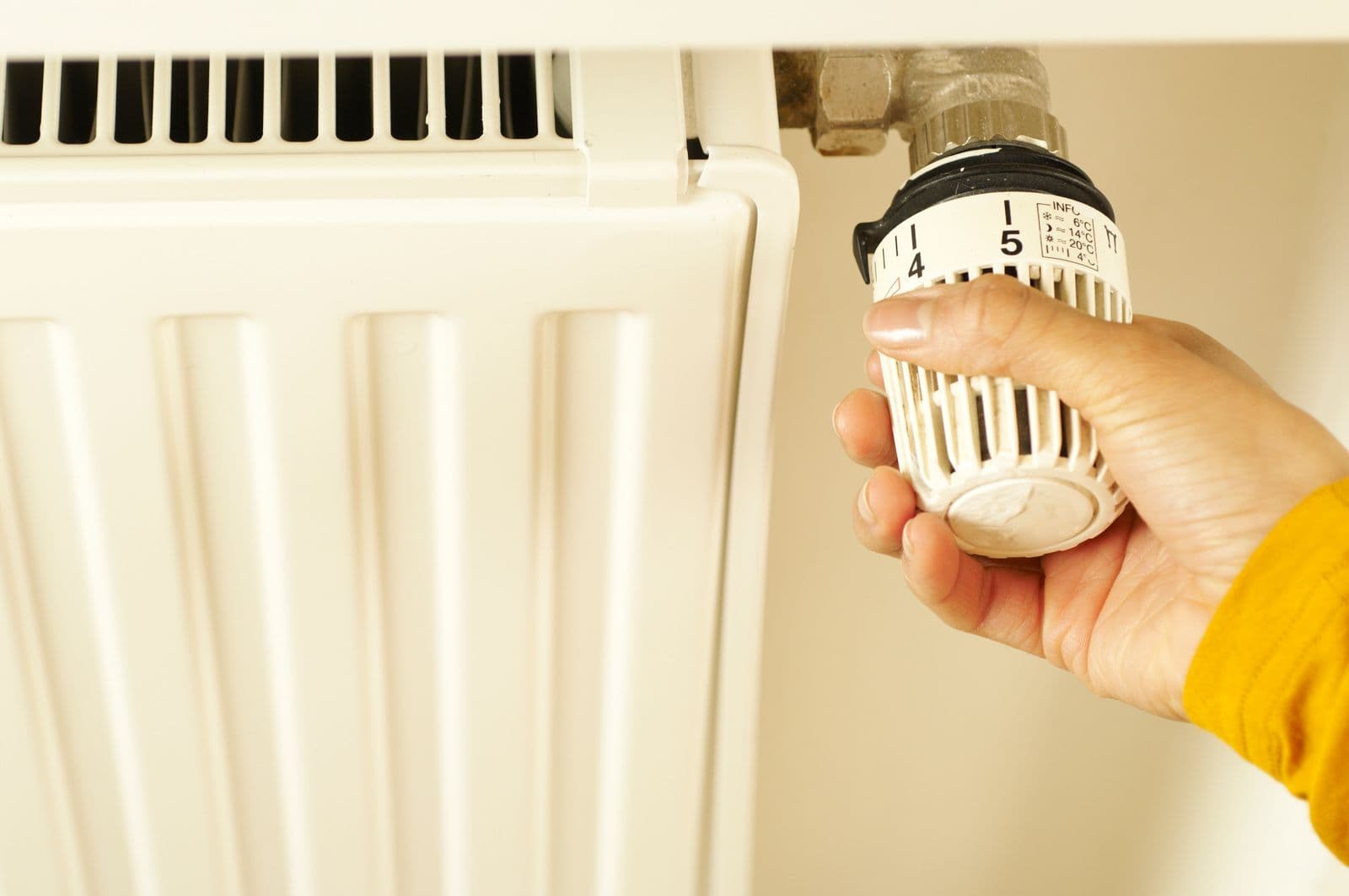 Hand draait aan een thermostaatknop op een radiator
